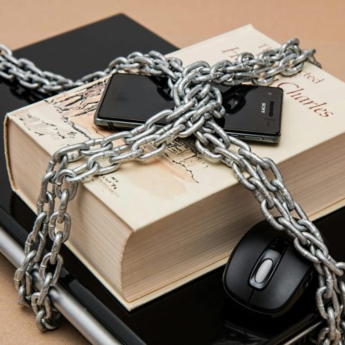 Chain-locked book, phone, and laptop symbolizing digital and intellectual security.