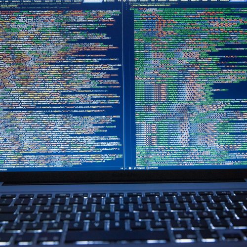 Laptop displaying source code with dual screens for software development.
